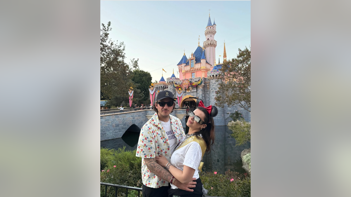 Bella Thorne and her fiancé Mark Emms posing together in front of Sleeping Beauty Castle at Disneyland during her 28th birthday celebration in Anaheim, Calif., on Oct. 10, 2025